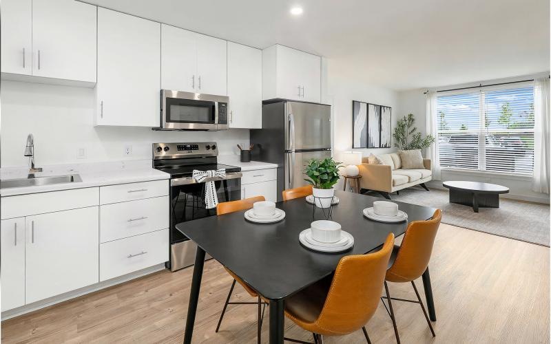 a spacious kitchen with ample light, wood-style flooring and white cabinets