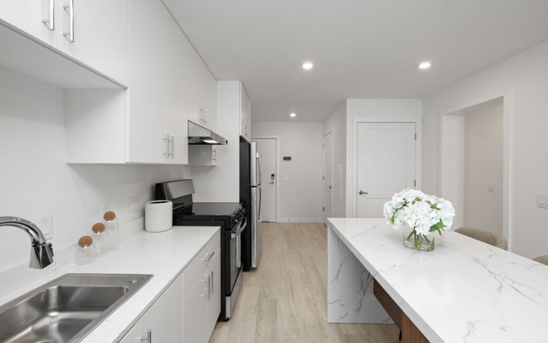 A spacious kitchen with ample light, wood-style flooring and white cabinets at The Randall apartments for rent in Woodbury Heights, New Jersey.
