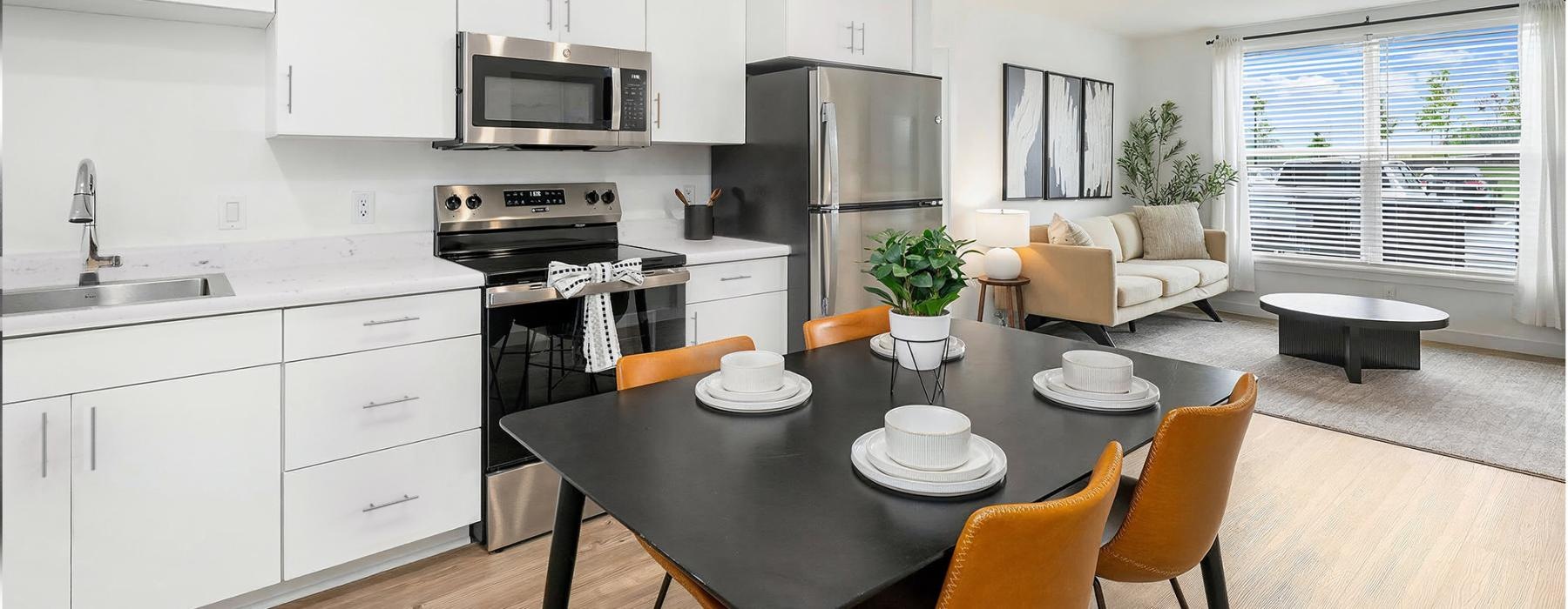 a spacious kitchen with ample light, wood-style flooring and white cabinets